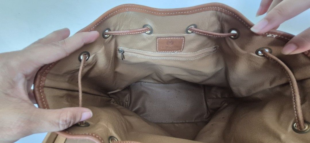 St. Marino Two-Tone Bucket Bag (Category: Shoulder Bags) located in Manila. Submitted by shandarfa49055 (Listing ID 1465839446, Image 3). Description: - Brand: St. Marino - Style: Bucket bag in black textured leather - Details: Brown leather trim and base, gold-tone eyelets, drawstring closure - Interior: Fabric lining with a zippered pocket and brand patch - Condition: Good, with some surface scuffs and scratches on the bottom brown leather port