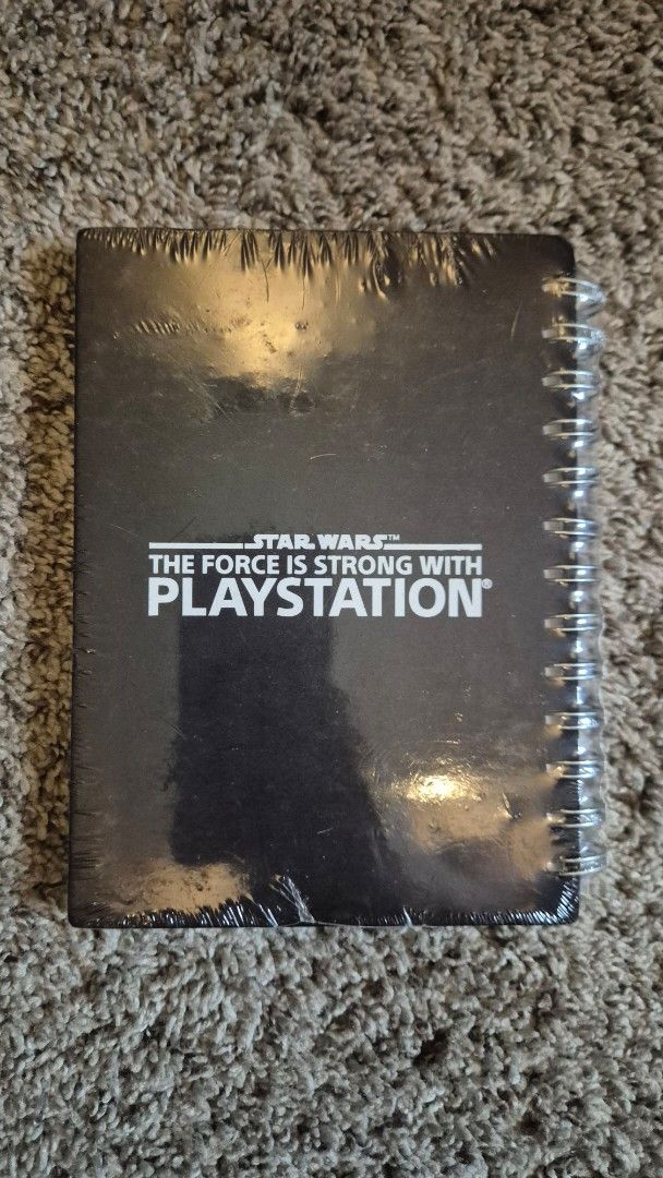 Star Wars PlayStation Notebook Spiral Bound (Category: Laptops & Notebooks) located in Muntinlupa City. Submitted by lazoftoys (Listing ID 1465773289, Image 2). Description: - Brand: Star Wars x PlayStation - Condition: Brand new, still sealed in original plastic wrap - Design: Black cover with metallic window cutout - Quote: "The Force Is Strong With PlayStation" printed in white on the back - Binding: Top spiral bound with silver rings.