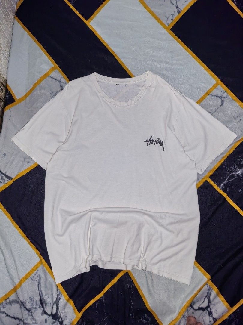 Stüssy Fish and Rose Graphic White Tee (Category: Tshirts & Polo Shirts ) located in Mabitac. Submitted by kitothrifty (Listing ID 1465862099, Image 2). Description: - Brand: Stüssy - Color: White - Fit: Regular fit, short sleeves, crew neck - Material: Soft cotton - Design: Small black Stüssy logo on left chest - Back Graphic: Large distressed print featuring the Stüssy signature logo stacked above a fish with a red rose - Condition: Brand new /