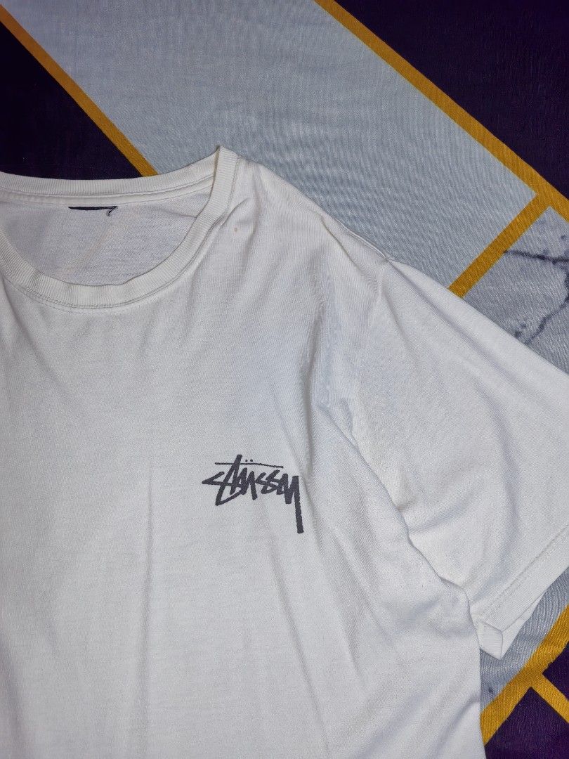 Stüssy Fish and Rose Graphic White Tee (Category: Tshirts & Polo Shirts ) located in Mabitac. Submitted by kitothrifty (Listing ID 1465862099, Image 3). Description: - Brand: Stüssy - Color: White - Fit: Regular fit, short sleeves, crew neck - Material: Soft cotton - Design: Small black Stüssy logo on left chest - Back Graphic: Large distressed print featuring the Stüssy signature logo stacked above a fish with a red rose - Condition: Brand new /