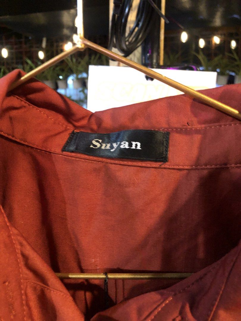 Suyan Brick Red Long Sleeve Button-Up Shirt (Category: Longsleeves) located in Cauayan City . Submitted by wholly.craaaft (Listing ID 1465876845, Image 2). Description: - Brand: Suyan - Color: Brick red - Fit: Relaxed fit with a curved hem - Details: Long sleeves, classic collar, single front pocket, standard button-down closure - Material: Soft and comfortable - Versatile basic piece, great for layering or wearing solo with jeans or slacks.
