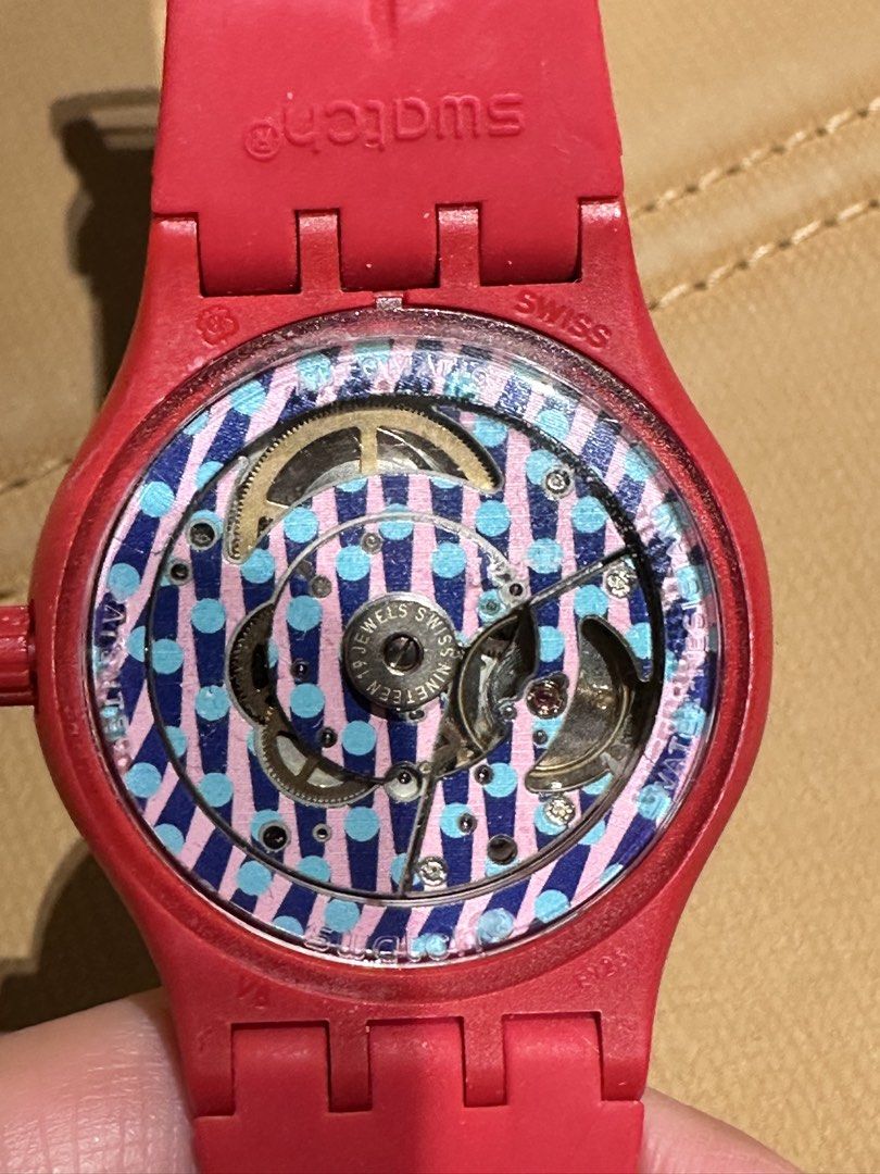Swatch Sistem Corrida Automatic Watch Red (Category: Women's Watches) located in Digos. Submitted by ijael1225 (Listing ID 1465921116, Image 3). Description: - Model: Swatch Sistem Corrida Automatic Watch - Dial: Textured silver with geometric cube pattern, black hands, and date window at 6 o'clock - Caseback: Exhibition back revealing a vibrant blue and pink polka dot pattern - Strap: Comfortable red silicone with buckle closure - Movement: Swis