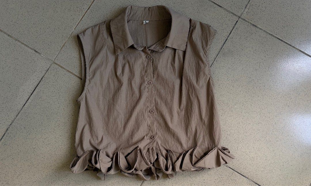 Taupe Sleeveless Button-Up Ruffle Hem Top (Category: Sleeveless) located in Makati City. Submitted by makatigirlpreloved (Listing ID 1465844718, Image 1). Description: - Color: Taupe - Style: Sleeveless top with front buttons and a sharp collar - Unique Detail: Large asymmetrical ruffled hem running down one side - Material: Lightweight and breathable - Condition: Great addition to any casual outfit - Mode of Payment: GCash or BPI - Shipping: Via