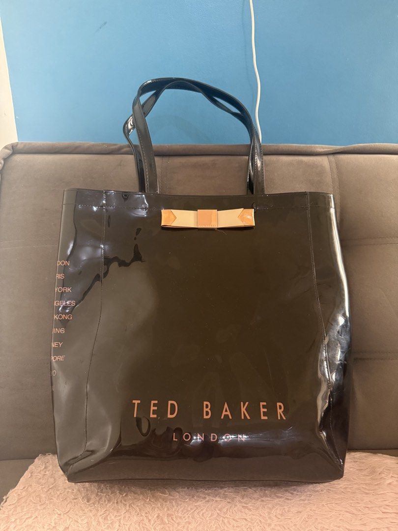 Ted Baker Black Patent Tote Bag with Bow (Category: Tote Bags) located in Malolos. Submitted by gb_21895 (Listing ID 1465951171, Image 2). Description: - Brand: Ted Baker London - Material/Finish: Black patent finish with rose gold hardware - Design Details: Statement bow on front, bold branding at the bottom, and global city names on side gussets - Storage: Roomy main compartment with an interior zip pocket on the back wall - Straps: Double shou