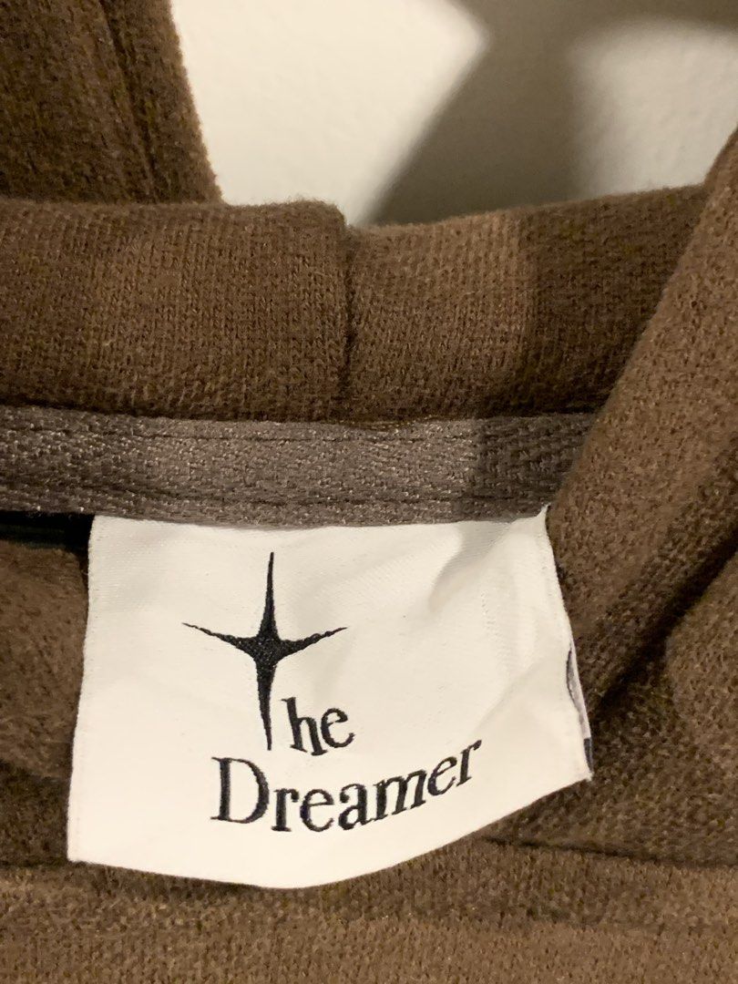 The Dreamer Brown Hoodie (Category: Coats, Jackets and Outerwear) located in Don Carlos. Submitted by buddysemaj (Listing ID 1465922484, Image 2). Description: - Brand: The Dreamer - Color: Brown - Fit: Relaxed, oversized - Details: White star graphic on chest and left cuff - Features: Front pouch pocket, thick hood, and ribbed cuffs and hem - Condition: Brand new/Excellent (Ready to wear).