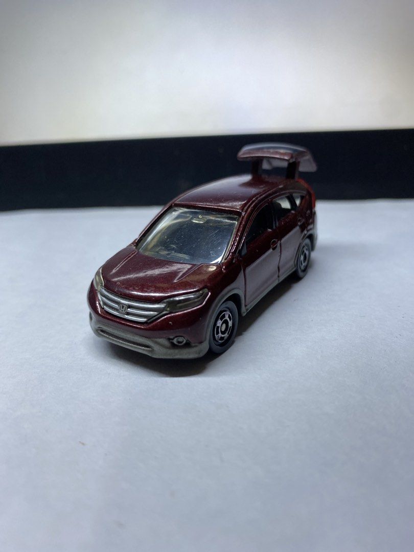 Tomica Honda CR-V Diecast (Category: Vehicle & Diecast Models) located in Paranaque City. Submitted by marcobotin (Listing ID 1465945398, Image 1). Description: - Brand: Tomica - Model: Honda CR-V in metallic maroon - Features: Opening rear trunk showing cargo area, detailed silver grille, headlights, and wheels - Mobility: Smooth rolling wheels - Condition: Paint chipping near the rear bumper and left rear light area.
