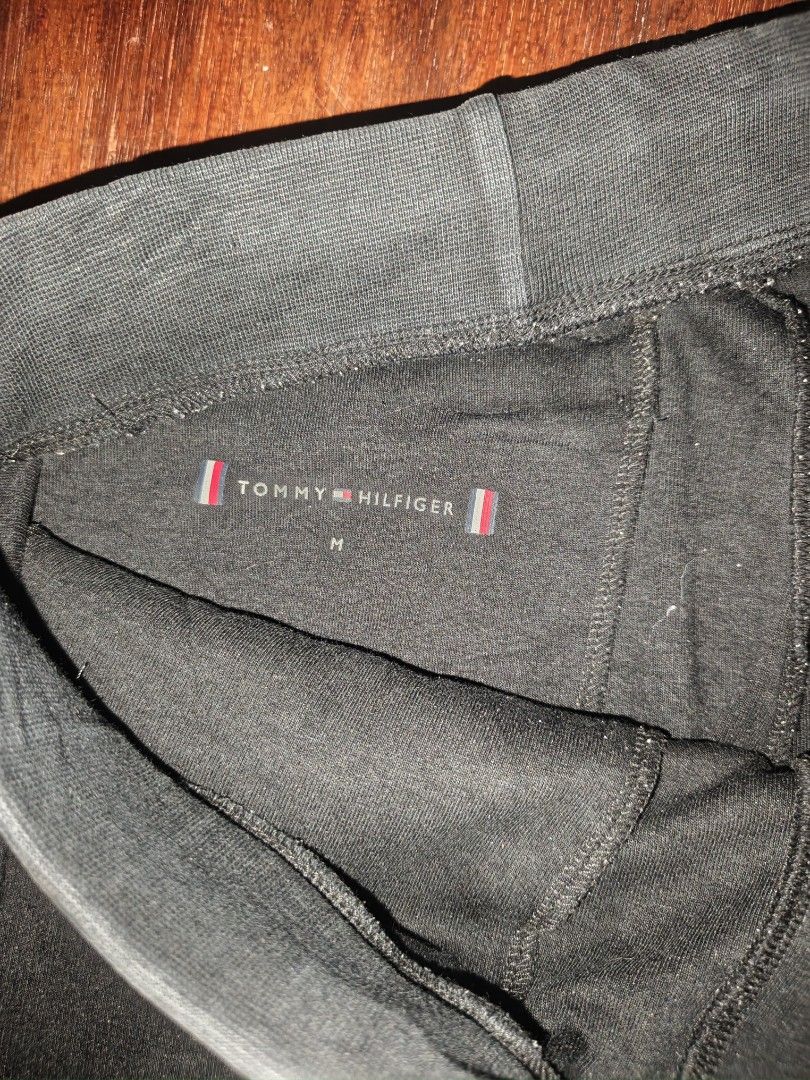 Tommy Hilfiger Black Sweatpants Joggers Medium (Category: Joggers) located in Manila. Submitted by esteemed_shop (Listing ID 1465896772, Image 2). Description: Tommy Hilfiger black sweatpants. Men's medium size, 175/84B. Elastic waistband with a drawstring. Ribbed cuffs at the ankles. Small Tommy Hilfiger flag logo embroidery near the pocket. Pocket on the back right side with flag accent. Inside tag shows code MW0MW22924. Clean condition, no tea