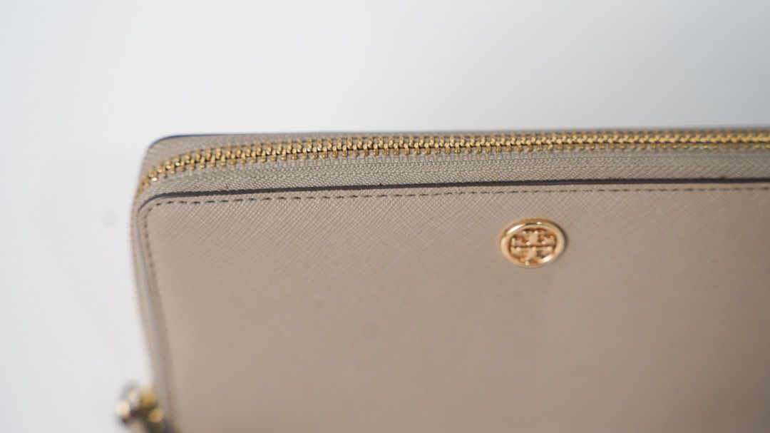 Tory Burch Saffiano Leather Wristlet Wallet Grey (Category: Luxury Bags & Wallets) located in Pasig City. Submitted by laagn.ph (Listing ID 1465764290, Image 1). Description: - Brand: Tory Burch - Material: Premium Saffiano leather in versatile grey - Hardware: Gold-tone with iconic front logo plaque - Features: Secure zip-around closure and matching detachable wrist strap - Interior: Standard size with plenty of slots for cards and cash - Condit