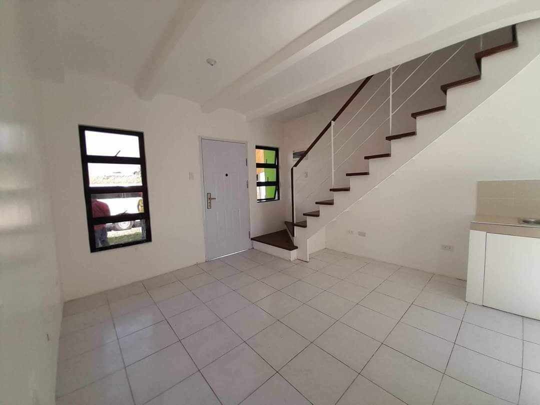 Townhouse for Pasalo (Category: House & Lot) located in Caloocan City. Submitted by valdestamo77709 (Listing ID 1465857471, Image 3). Description: - Unfurnished townhouse unit ready for occupancy - Open-concept living area downstairs - Kitchen counter equipped with a built-in sink - Clean tiled flooring throughout - Elegant wooden staircase with white railings - 1 functional bathroom with toilet, sink, and shower head - Stylish white and brown ex