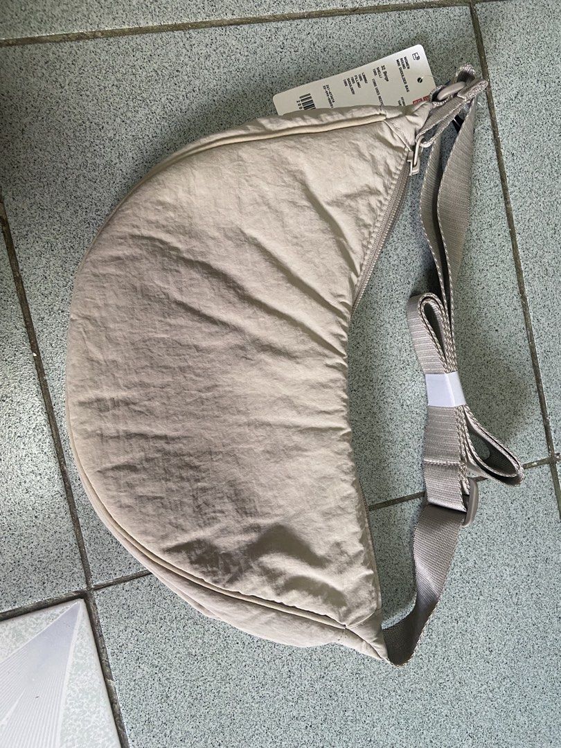 Uniqlo Round Mini Shoulder Bag Beige (Category: Shoulder Bags) located in Silang. Submitted by Apple_Mac07 (Listing ID 1465833939, Image 1). Description: - Authentic Uniqlo Round Mini Shoulder Bag in Beige - Brand new with original store tag attached - Trendy crescent shape with an adjustable strap - Smooth, durable nylon fabric with secure zip closure - Practical inner pockets to keep your essentials organized - Perfect for daily use, errands, a