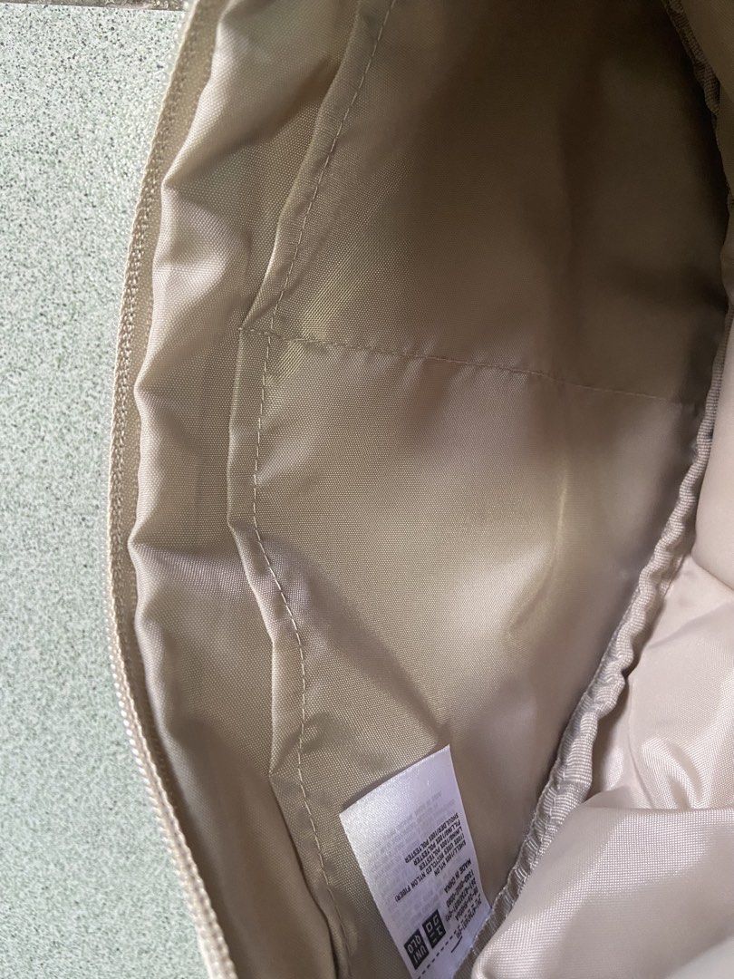 Uniqlo Round Mini Shoulder Bag Beige (Category: Cross-body Bags) located in Silang. Submitted by Apple_Mac07 (Listing ID 1465834473, Image 2). Description: - Brand: Uniqlo - Item: Round Mini Shoulder Bag - Color: Versatile Neutral Beige (matches everything) - Material: Durable nylon shell with fully lined interior - Features: Iconic crescent shape, adjustable strap with buckle closure, secure zip top opening - Organization: Two internal slip pock