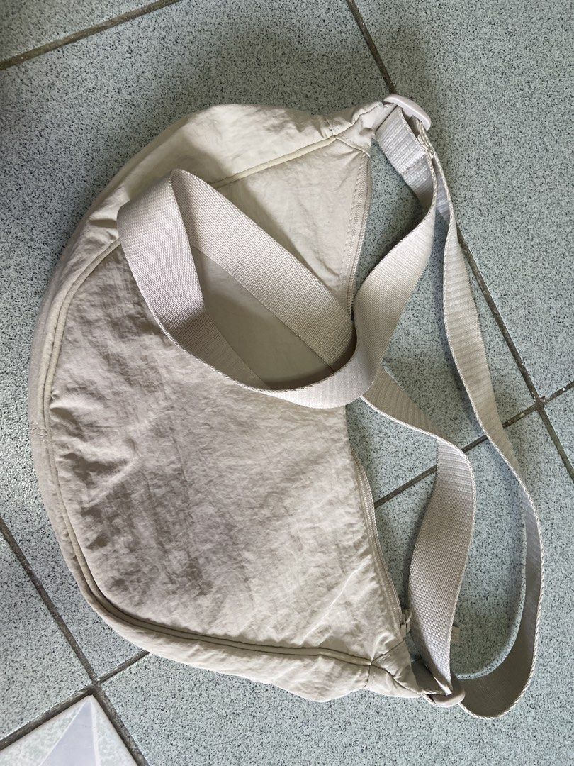 Uniqlo Round Mini Shoulder Bag Beige (Category: Cross-body Bags) located in Silang. Submitted by Apple_Mac07 (Listing ID 1465834473, Image 1). Description: - Brand: Uniqlo - Item: Round Mini Shoulder Bag - Color: Versatile Neutral Beige (matches everything) - Material: Durable nylon shell with fully lined interior - Features: Iconic crescent shape, adjustable strap with buckle closure, secure zip top opening - Organization: Two internal slip pock