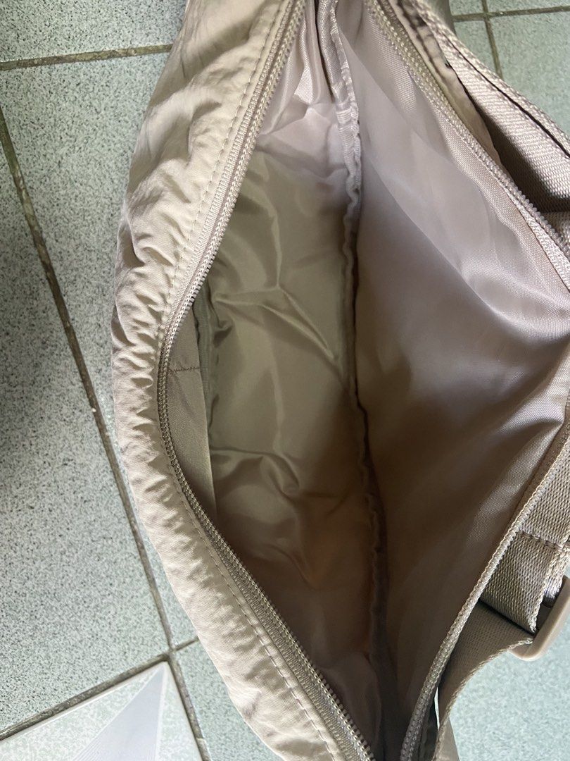Uniqlo Round Mini Shoulder Bag Beige (Category: Cross-body Bags) located in Silang. Submitted by Apple_Mac07 (Listing ID 1465834473, Image 3). Description: - Brand: Uniqlo - Item: Round Mini Shoulder Bag - Color: Versatile Neutral Beige (matches everything) - Material: Durable nylon shell with fully lined interior - Features: Iconic crescent shape, adjustable strap with buckle closure, secure zip top opening - Organization: Two internal slip pock