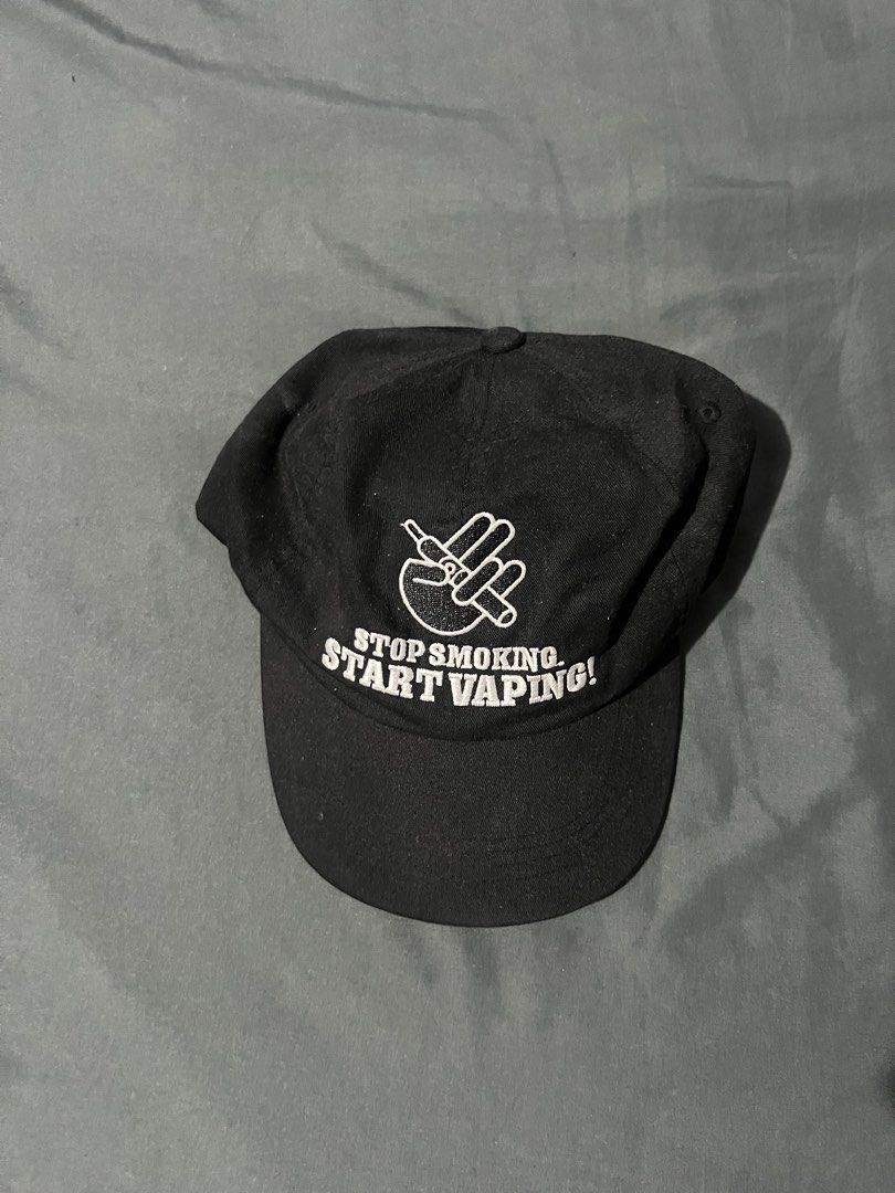 Vape Cap (Category: Caps & Hats) located in Manila. Submitted by shoptoji (Listing ID 1465774819, Image 1). Description: -9/10 condition - Color: Black - Style: Unstructured baseball cap with standard curved brim - Front Design: White embroidery featuring a graphic hand sign holding a vape pen and 'STOP SMOKING. START VAPING!' text - Closure: Adjustable strapback at the rear - Condition: Clean fabric, no noticeable fading or wear.