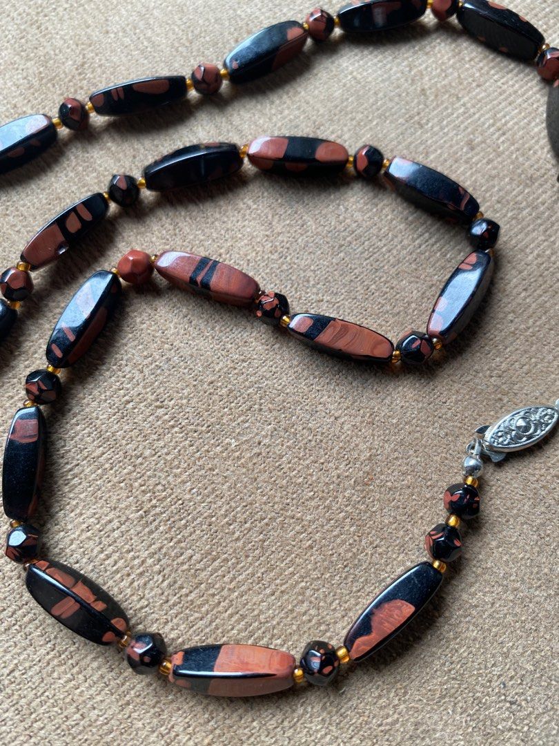 Vintage obsidian necklace (Category: Other Accessories) located in Cebu City. Submitted by janb85 (Listing ID 1465853848, Image 3). Description: A vintage beaded tokachi stone (obsidian) necklace featuring polished, elongated barrel-shaped and round gemstone beads in contrasting shades of terracotta red and deep black, separated by small golden seed beads and finished with a patterned silver-tone clasp..