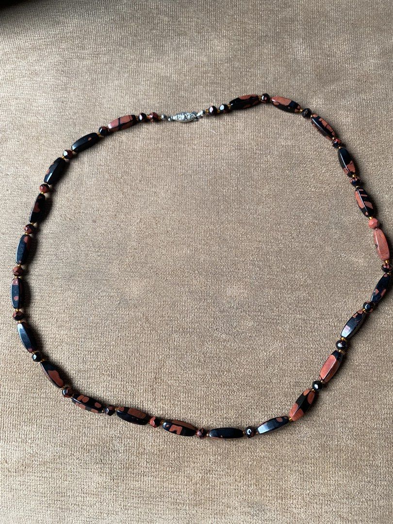 Vintage obsidian necklace (Category: Other Accessories) located in Cebu City. Submitted by janb85 (Listing ID 1465853848, Image 2). Description: A vintage beaded tokachi stone (obsidian) necklace featuring polished, elongated barrel-shaped and round gemstone beads in contrasting shades of terracotta red and deep black, separated by small golden seed beads and finished with a patterned silver-tone clasp..