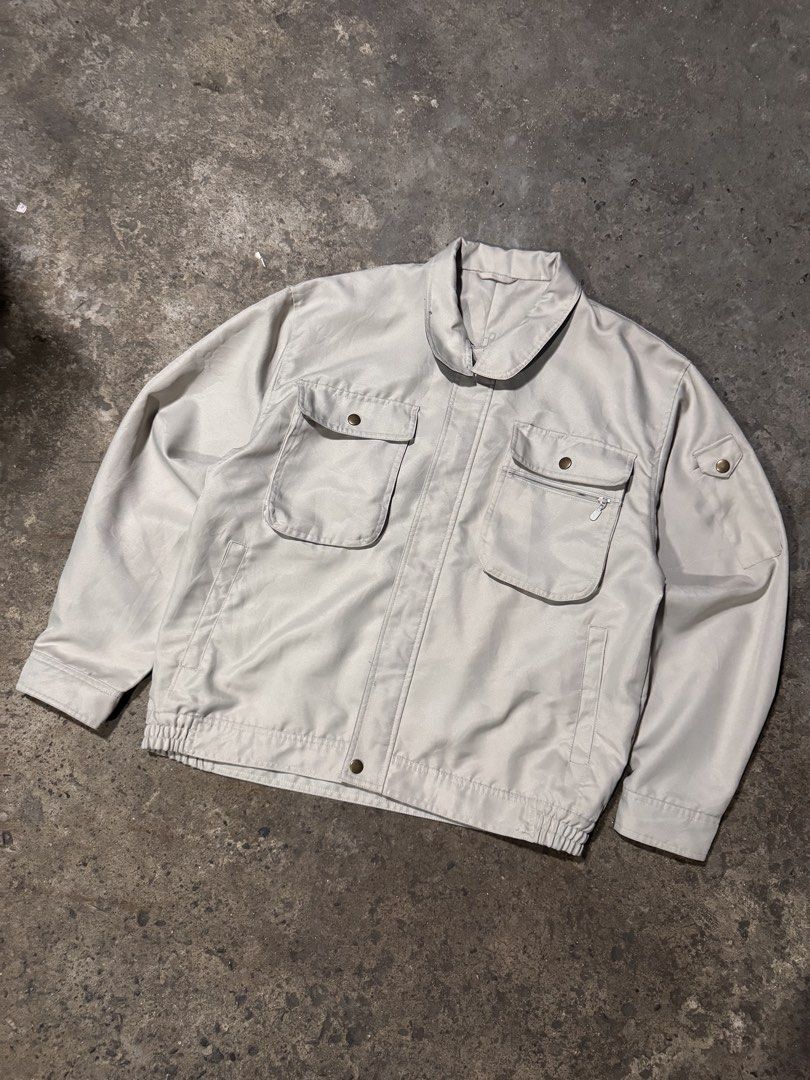 Vintage Utility Work Jacket Beige (Category: Coats, Jackets and Outerwear) located in Pasig City. Submitted by dripthrift1600 (Listing ID 1465950259, Image 1). Description: - Color: Beige - Style: Workwear jacket - Closure: Front button closure - Pockets: Buttoned chest pockets, zippered compartment, and extra sleeve pocket - Fit: Elasticated hem at the back for a relaxed fit - Condition: Clean fabric and solid hardware throughout - Dimes: 22x24.