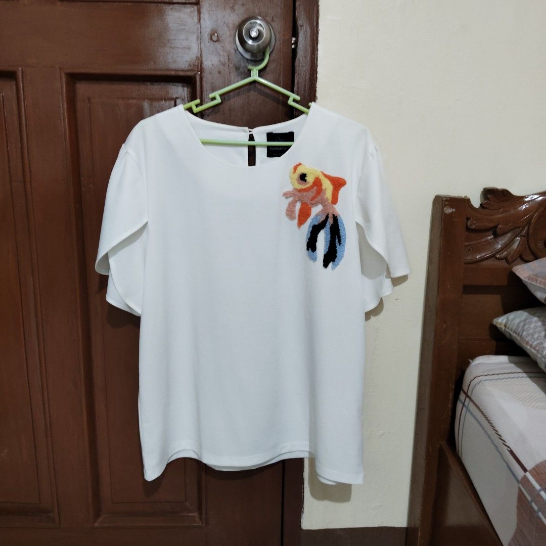 White blouse with colorful embroidered goldfish patch (Category: Blouses) located in Tabaco. Submitted by kooki24 (Listing ID 1465950349, Image 1). Description: - Color: White - Style: Casual short-sleeved blouse with trendy flared bell sleeves - Detail: Vibrant, textured goldfish patch embroidered on the chest - Back: Elegant keyhole back closure - Condition: Clean fabric, excellent for everyday wear - Mode of Payment: GCash or BPI - Shipping: S