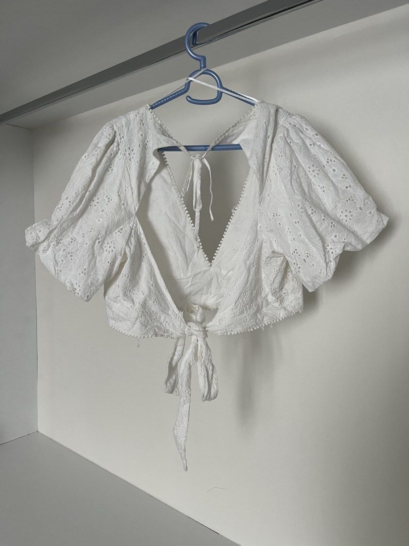 White Eyelet Crop Top Open Back Tie Front (Category: Sleeveless) located in Quezon City. Submitted by cooperminie (Listing ID 1465810853, Image 2). Description: - Color: White with all-over floral embroidery - Style: Crop top with trendy puff sleeves - Neckline: Deep plunge bordered with tiny pom poms - Back: Open back design with dual string ties and bottom knot - Fabric: Lightweight and breathable - Condition: Has some loose threads but unnotic