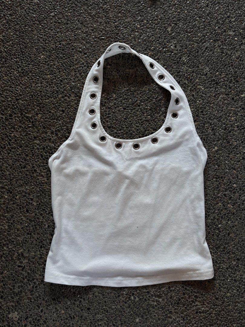 White halter top with silver grommets and eyelets (Category: Sleeveless) located in San Fernando. Submitted by gigikyla (Listing ID 1465925522, Image 1). Description: - Style: Y2K casual sleeveless halter top - Fit: Fitted style through the body - Details: Decorated with rows of metal eyelets and grommets on the collar and neckline strap - Material: Soft and comfortable cotton stretch fabric.