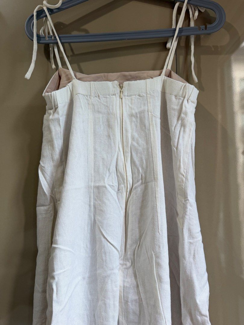White linen mini dress (Category: Dresses) located in Pasay City. Submitted by closetbykim (Listing ID 1465786656, Image 3). Description: - Size: Fits XS-M frame - Style: White mini dress, great for casual outings or dates - Straps: Adjustable tie straps on the shoulders - Closure: Back zipper closure - Lining: Fully lined with beige fabric - Material: Textured linen-like material - Condition: Worn a few times, washed, clean inside and out, and r