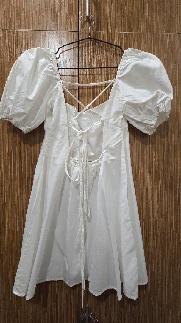 White Puff Sleeve Mini Dress (Category: Dresses) located in Cebu City. Submitted by kitty_12345_ (Listing ID 1465877960, Image 3). Description: - Brand: Sunday Classics - Color: White - Style: Mini dress with sweetheart neckline and gathered bust - Sleeves: Short puff sleeves with elastic cuffs - Back: Open back with crisscross straps and tie closure - Fabric: Lightweight and breathable - Condition: Excellent / Like new - Perfect for: Casual outi