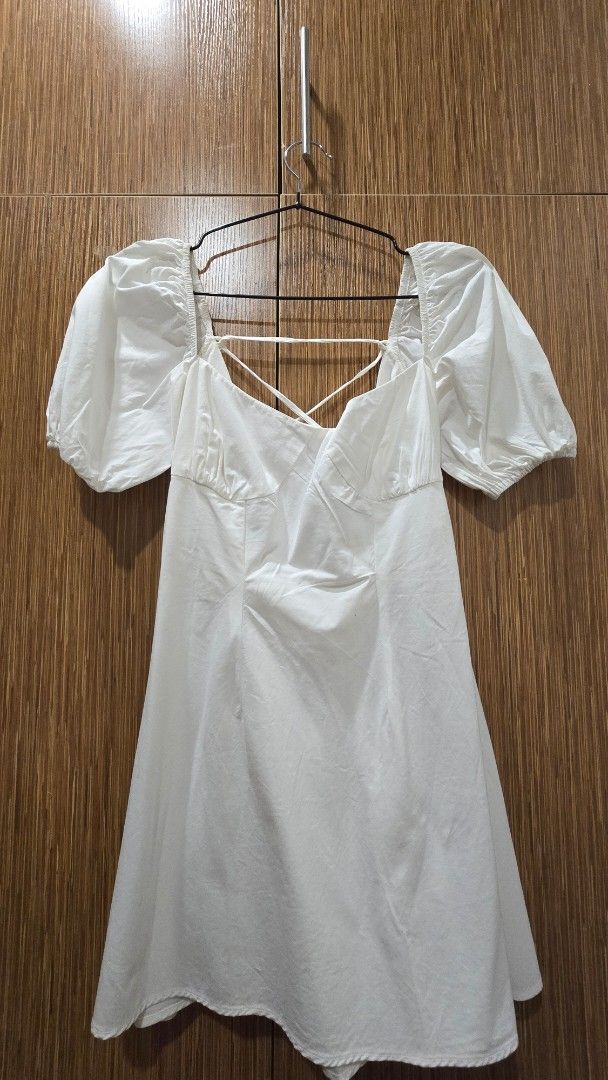 White Puff Sleeve Mini Dress (Category: Dresses) located in Cebu City. Submitted by kitty_12345_ (Listing ID 1465877960, Image 2). Description: - Brand: Sunday Classics - Color: White - Style: Mini dress with sweetheart neckline and gathered bust - Sleeves: Short puff sleeves with elastic cuffs - Back: Open back with crisscross straps and tie closure - Fabric: Lightweight and breathable - Condition: Excellent / Like new - Perfect for: Casual outi