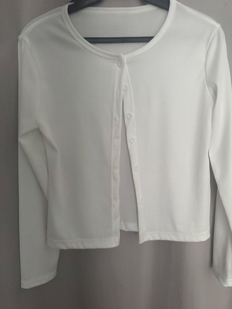 White ribbed long sleeve button down cardigan top (Category: Longsleeves) located in Manila. Submitted by decluterthings888 (Listing ID 1465953409, Image 2). Description: - Color: Classic white - Material: Soft, stretchy ribbed knit fabric - Design: Round neckline, long sleeves, and matching front buttons - Fit: Cropped length, perfect for high-waisted jeans or skirts - Condition: Clean and well-maintained - Style: Versatile basic layering piece.