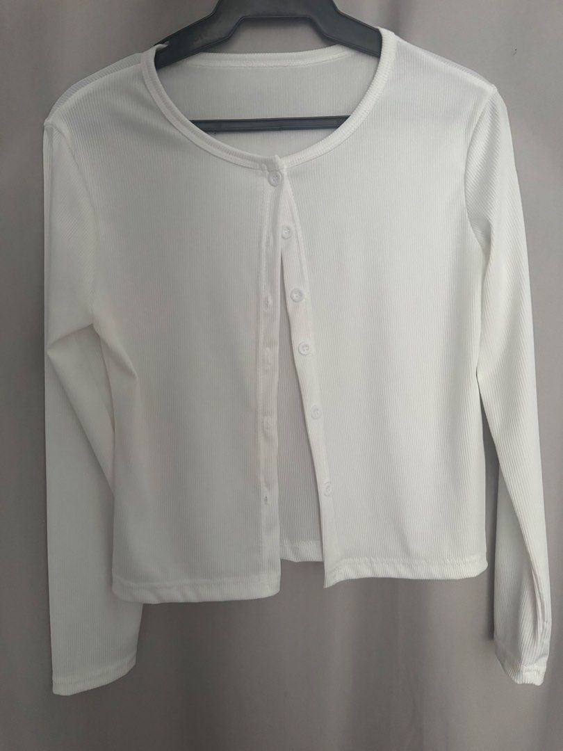White ribbed long sleeve button down cardigan top (Category: Longsleeves) located in Manila. Submitted by decluterthings888 (Listing ID 1465953409, Image 1). Description: - Color: Classic white - Material: Soft, stretchy ribbed knit fabric - Design: Round neckline, long sleeves, and matching front buttons - Fit: Cropped length, perfect for high-waisted jeans or skirts - Condition: Clean and well-maintained - Style: Versatile basic layering piece.