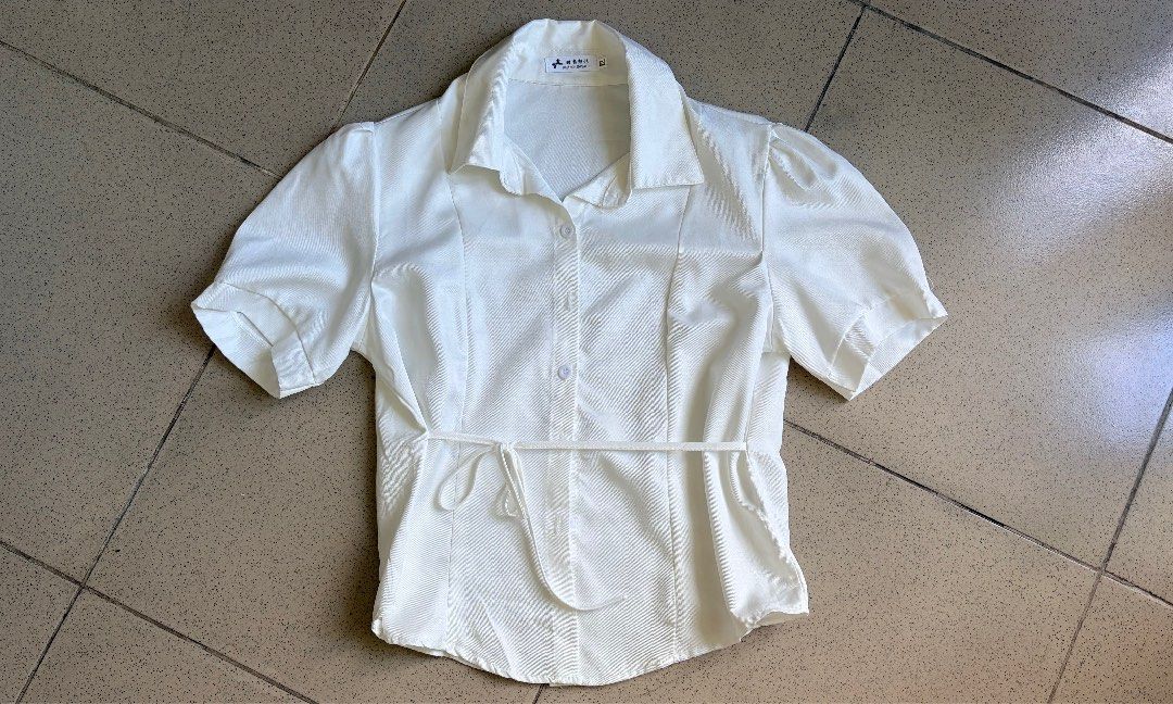 White Short Sleeve Button-Down Blouse With Tie Waist (Category: Blouses) located in Makati City. Submitted by makatigirlpreloved (Listing ID 1465845099, Image 1). Description: - Color: Clean solid white - Style: Short sleeve button-down with classic lapel collar - Feature: Includes a matching waist tie belt to cinch the silhouette - Fabric: Lightweight and comfortable for all-day wear - Versatility: Perfect for casual daily outfits or office wear
