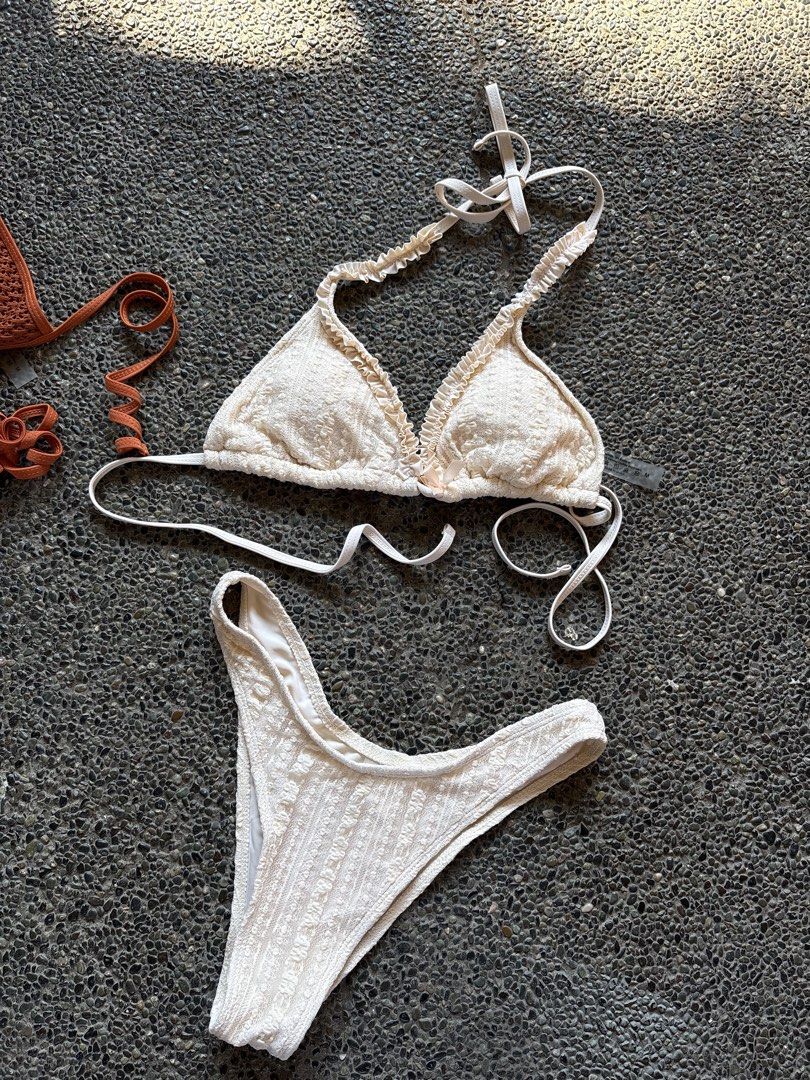 White Textured Ruffle Triangle Bikini Set (Category: Bikinis & Swimsuits) located in San Fernando. Submitted by gigikyla (Listing ID 1465925295, Image 1). Description: - Color: White - Style: Two-piece bikini set with an all-over textured fabric pattern - Top: Triangle cut with delicate ruffled edges and adjustable tie straps - Bottoms: Cheeky cut design - Condition: Clean, no stains or flaws noted - Ideal for: Beach days and pool lounging.