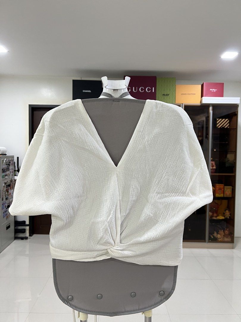 White V-neck top with front knot detail (Category: Blouses) located in Manila. Submitted by imprincessg888 (Listing ID 1465850658, Image 1). Description: - Color: Cream / Off-white - Material: Textured fabric - Design: Reversible (wear V-neck front or back) - Details: Unique twisted knot at the front hem - Sleeves: Loose draped batwing sleeves - Style: Casual, easy to pair with jeans or skirts.