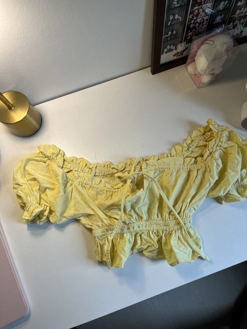 Yellow off-shoulder crop top with ruffles and tie string (Category: Sleeveless) located in Bacolod City. Submitted by miffywhitematcha (Listing ID 1465921597, Image 1). Description: - Color: Bright yellow - Style: Off-shoulder crop top with tie-front detail - Sleeves: Short puff sleeves with elastic cuffs - Fit: Smocked bodice and ruffled hem - Material: Lightweight fabric, perfect for sunny days.