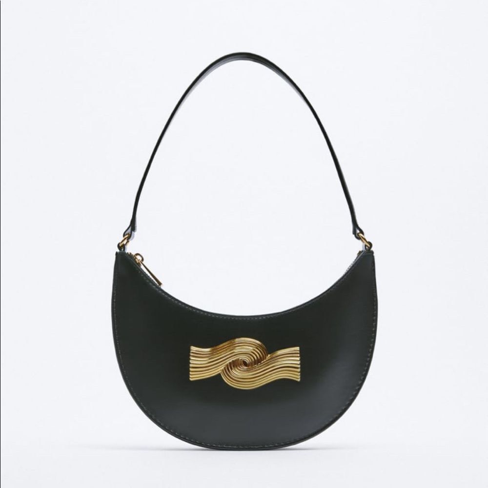 Zara Black Crescent Shoulder Bag with Gold Wave Hardware (Category: Shoulder Bags) located in Quezon City. Submitted by cndcvrtc (Listing ID 1465945401, Image 2). Description: - Style: Black crescent-shaped shoulder bag with clean lines - Design: Features a striking gold metallic wave sculpture on the front - Details: Smooth finish, secure zip top closure, and thin strap - Capacity: Compact size that easily fits your phone and daily essentials - 