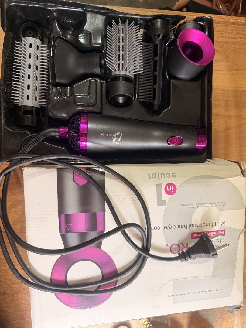 5 in 1 Multifunctional Hair Dryer Comb Styling Tool (Category: Hair) located in Oas. Submitted by joice_29 (Listing ID 1465973621, Image 1). Description: 5-in-1 multifunctional hair styling tool and dryer set by Binnis. Dark grey and pink colorway. Includes main handle with power cord, multiple interchangeable attachments like round brushes, smoothing brush, and drying nozzle. Original packaging box included. Everything neatly fits in the molded 