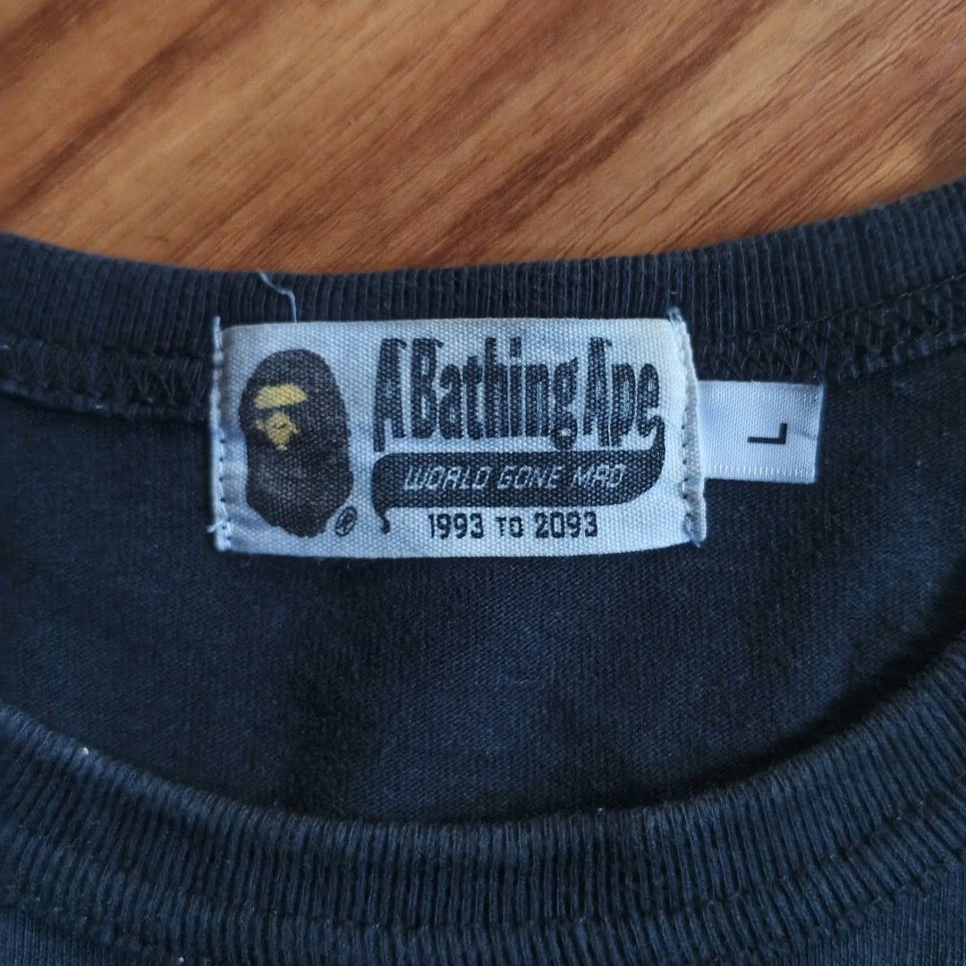 A Bathing Ape BAPE Ape Head Pocket Tee Black Size L (Category: Tshirts & Polo Shirts ) located in Paranaque City. Submitted by thriftine5 (Listing ID 1466011091, Image 2). Description: - Brand: A Bathing Ape (BAPE) - Color: Black - Size: L - Material: 100% Cotton - Design: Crew neck with light camo front pocket and peeking ape head graphic - Tags: World Gone Mad collar tag (1993-2093), Made in China wash tag - Condition: Worn condition with norma