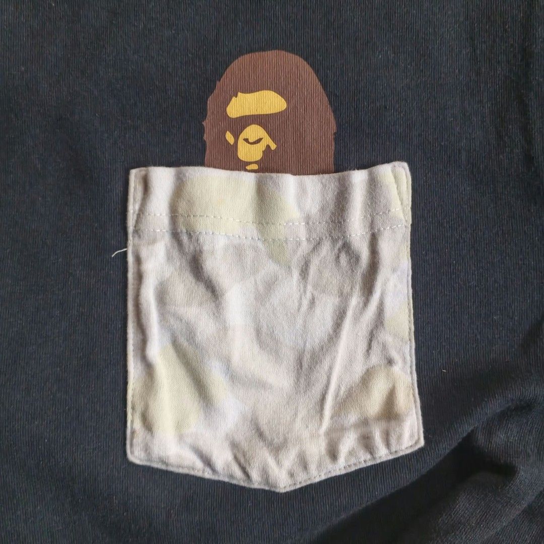 A Bathing Ape BAPE Ape Head Pocket Tee Black Size L (Category: Tshirts & Polo Shirts ) located in Paranaque City. Submitted by thriftine5 (Listing ID 1466011091, Image 3). Description: - Brand: A Bathing Ape (BAPE) - Color: Black - Size: L - Material: 100% Cotton - Design: Crew neck with light camo front pocket and peeking ape head graphic - Tags: World Gone Mad collar tag (1993-2093), Made in China wash tag - Condition: Worn condition with norma