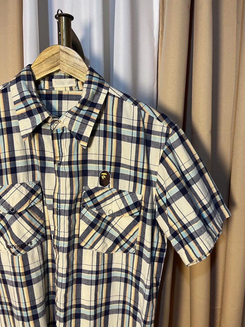 A Bathing Ape BAPE Plaid Short Sleeve Button-Down Shirt (Category: Tshirts & Polo Shirts ) located in Kidapawan. Submitted by azythrift (Listing ID 1466051028, Image 2). Description: - Brand: A Bathing Ape (BAPE) off - Size Medium - Style: Short sleeve plaid button-down shirt - Design: Classic multi-color plaid pattern (white, navy blue, light blue, and yellow stripes) - Details: Dual front chest pockets with button flaps, iconic Bape head logo p