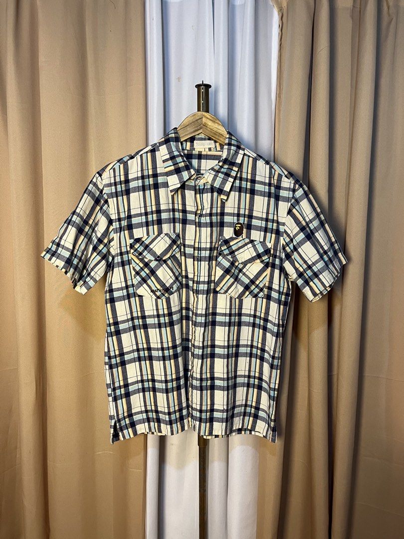 A Bathing Ape BAPE Plaid Short Sleeve Button-Down Shirt (Category: Tshirts & Polo Shirts ) located in Kidapawan. Submitted by azythrift (Listing ID 1466051028, Image 1). Description: - Brand: A Bathing Ape (BAPE) off - Size Medium - Style: Short sleeve plaid button-down shirt - Design: Classic multi-color plaid pattern (white, navy blue, light blue, and yellow stripes) - Details: Dual front chest pockets with button flaps, iconic Bape head logo p