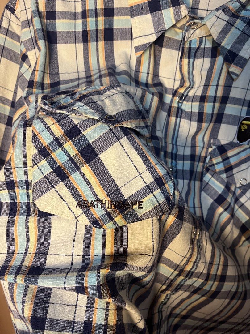 A Bathing Ape BAPE Plaid Short Sleeve Button-Down Shirt (Category: Tshirts & Polo Shirts ) located in Kidapawan. Submitted by azythrift (Listing ID 1466051028, Image 3). Description: - Brand: A Bathing Ape (BAPE) off - Size Medium - Style: Short sleeve plaid button-down shirt - Design: Classic multi-color plaid pattern (white, navy blue, light blue, and yellow stripes) - Details: Dual front chest pockets with button flaps, iconic Bape head logo p