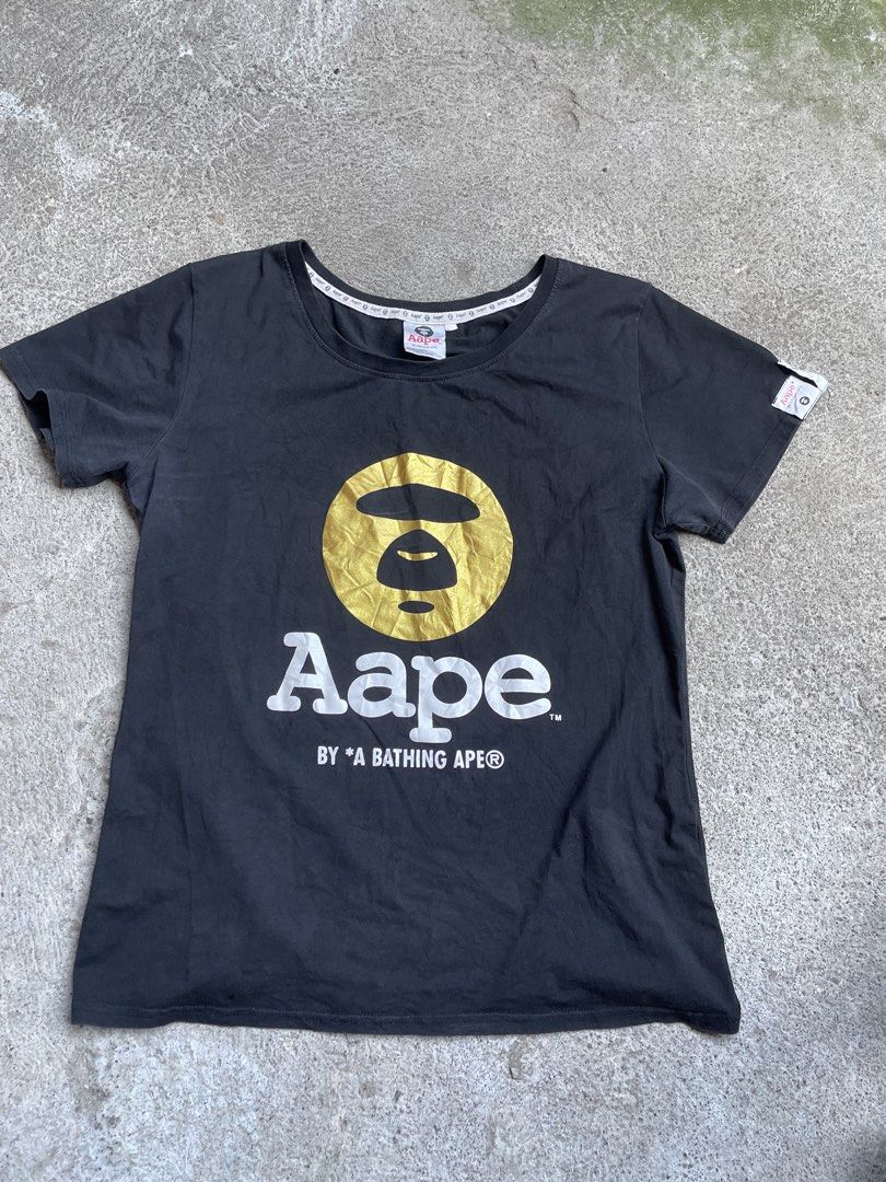 Aape By A Bathing Ape Black Graphic Tee (Category: Tshirts & Polo Shirts ) located in Siniloan. Submitted by rethr1ft (Listing ID 1466056040, Image 1). Description: - Brand: Aape by A Bathing Ape - Color: Black - Size: Regular fit, crew neck - Design: Large gold ape head graphic with white Aape lettering - Details: Signature branded inner collar tape and woven sleeve tags - Condition: 100% authentic, classic streetwear piece.