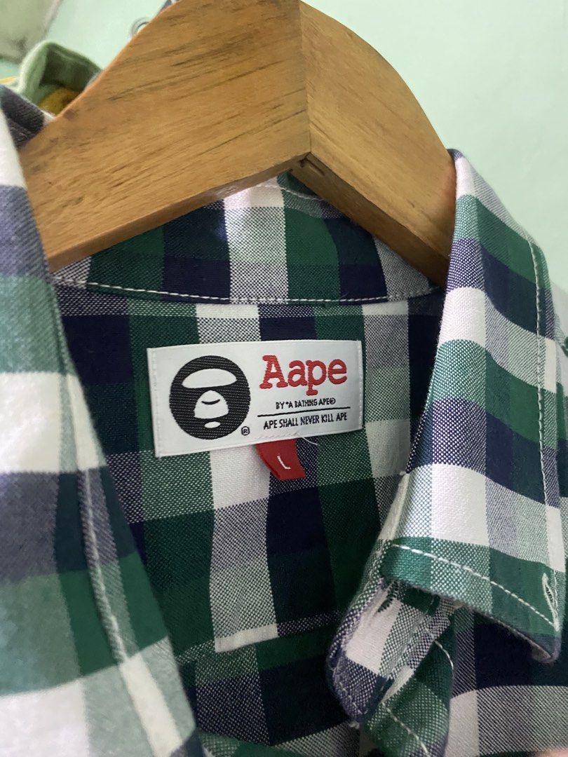 Aape By A Bathing Ape Green Plaid Button-Down Shirt (Category: Tshirts & Polo Shirts ) located in Tiaong. Submitted by maticbuy (Listing ID 1465966058, Image 3). Description: - Brand: Aape by A Bathing Ape - Design: Green and blue plaid short-sleeve shirt - Back Detail: Large white Ape head logo print - Chest Detail: Smaller embroidered logo patch on the pocket area - Closure: Button-down front with branded buttons - Size: L (verified via inner w