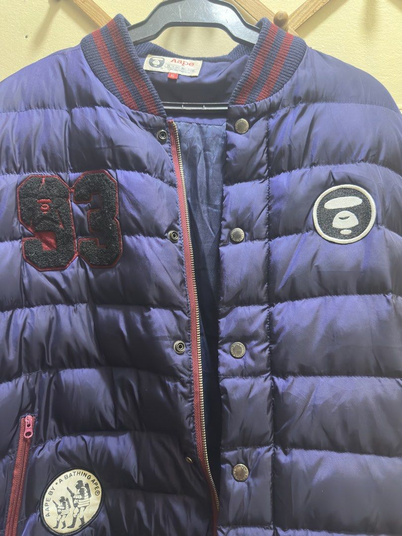 Aape By A Bathing Ape Puffer Bomber Jacket XL (Category: Coats, Jackets and Outerwear) located in Manila. Submitted by rarepenguin_a3187c (Listing ID 1466119931, Image 1). Description: - Brand: Aape by A Bathing Ape - Color: Blue and maroon - Size: XL (fits true to size) - Design: Bold '93' patch on right chest, circular monkey logo patch on left - Details: Striped ribbing on collar, cuffs, and hem - Closure & Pockets: Zip front with snap button 