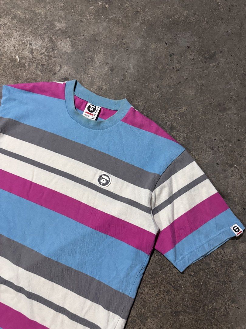 Aape By A Bathing Ape Striped T-Shirt (Category: Tshirts & Polo Shirts ) located in Pasig City. Submitted by dripthrift1600 (Listing ID 1466098046, Image 3). Description: - Brand: Aape by A Bathing Ape - Colorway: Blue, magenta, white, and grey stripes - Size: Medium (tag attached) - Design: Short sleeves, crew neckline - Details: Aape Now woven front tag, chest logo patch, left sleeve branding patch, and back collar label - Dimes: 22x27.