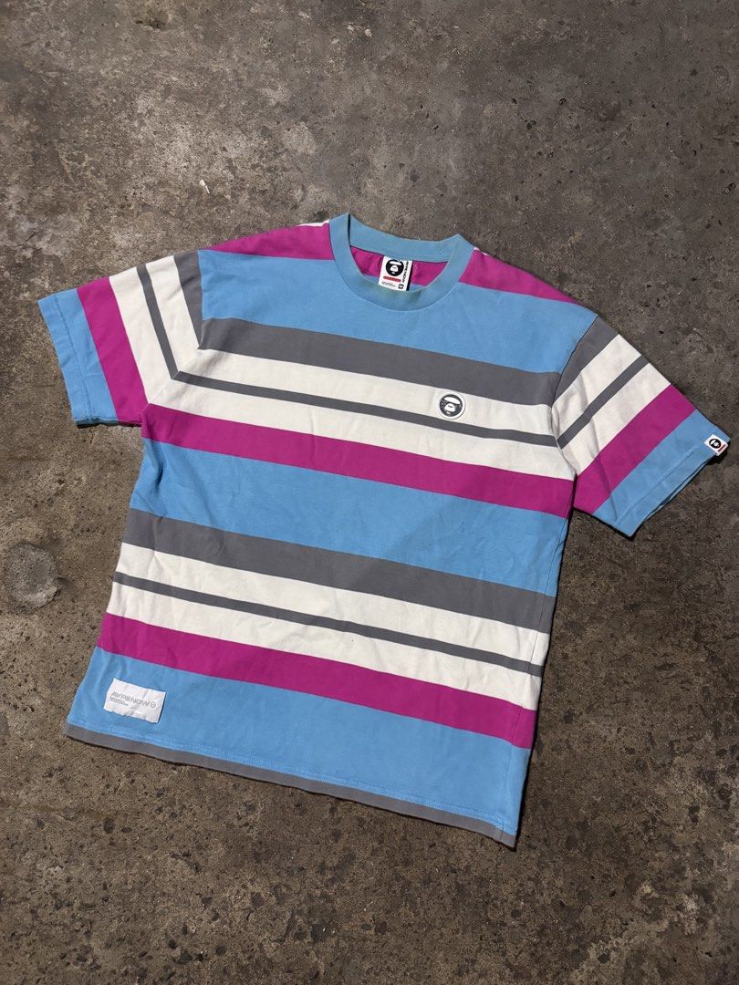 Aape By A Bathing Ape Striped T-Shirt (Category: Tshirts & Polo Shirts ) located in Pasig City. Submitted by dripthrift1600 (Listing ID 1466098046, Image 1). Description: - Brand: Aape by A Bathing Ape - Colorway: Blue, magenta, white, and grey stripes - Size: Medium (tag attached) - Design: Short sleeves, crew neckline - Details: Aape Now woven front tag, chest logo patch, left sleeve branding patch, and back collar label - Dimes: 22x27.