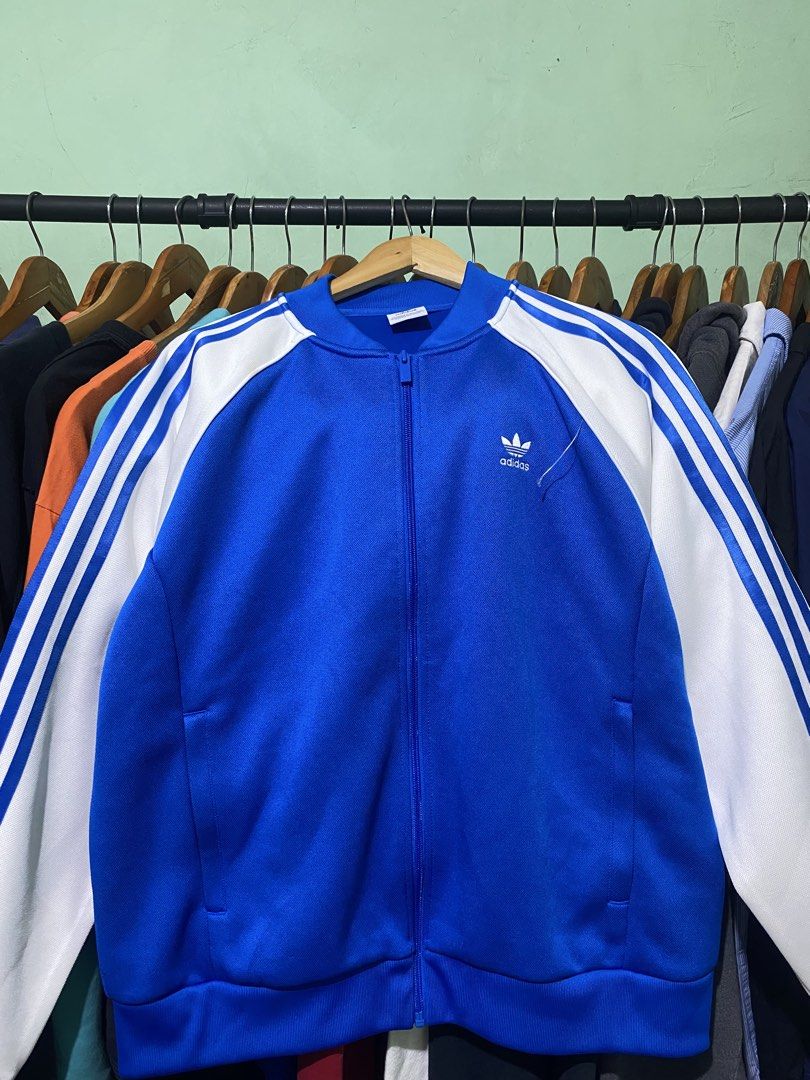 Adidas Blue White Track Jacket (Category: Coats, Jackets and Outerwear) located in Tiaong. Submitted by maticbuy (Listing ID 1465965693, Image 1). Description: - Brand: Adidas - Color: Bright blue with white stripes - Features: Full zip closure, stand-up collar, front pockets - Details: Embroidered Trefoil logo on chest - Condition: Clean fabric, ready to wear.
