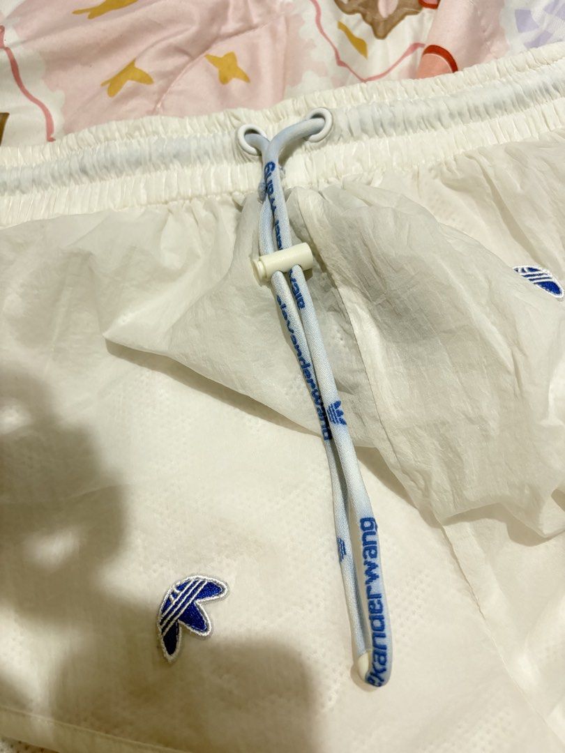 Adidas x Alexander Wang White Shorts (Category: Shorts) located in Makati City. Submitted by jrnhnnh3047116 (Listing ID 1466074465, Image 1). Description: - Brand: Adidas x Alexander Wang - Color: White - Material: Lightweight nylon with comfortable inner mesh lining - Waistband: Elastic drawstring with branded text print and adjustable toggle - Details: Multiple embroidered upside-down trefoil logos on front and back - Pockets: Back zipper pocke
