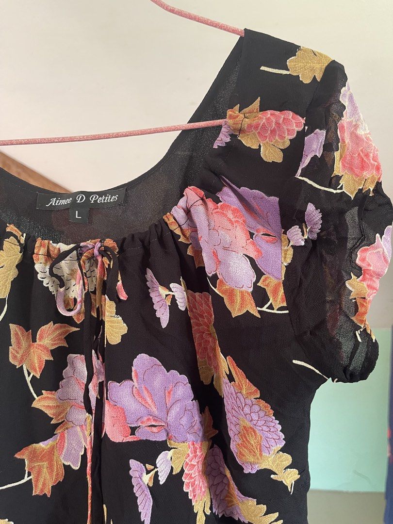 Aimee D Petites floral black blouse (Category: Blouses) located in Baybay. Submitted by shikita27906 (Listing ID 1466032983, Image 2). Description: - Brand: Aimee D Petites - Size: L but can fit M - Design: Black with pink, purple, and green floral print - Details: Scoop neckline with drawstring tie, short sleeves, lightweight fabric - Condition: Noticeable small fabric holes and wear near the flowers as shown in photos.