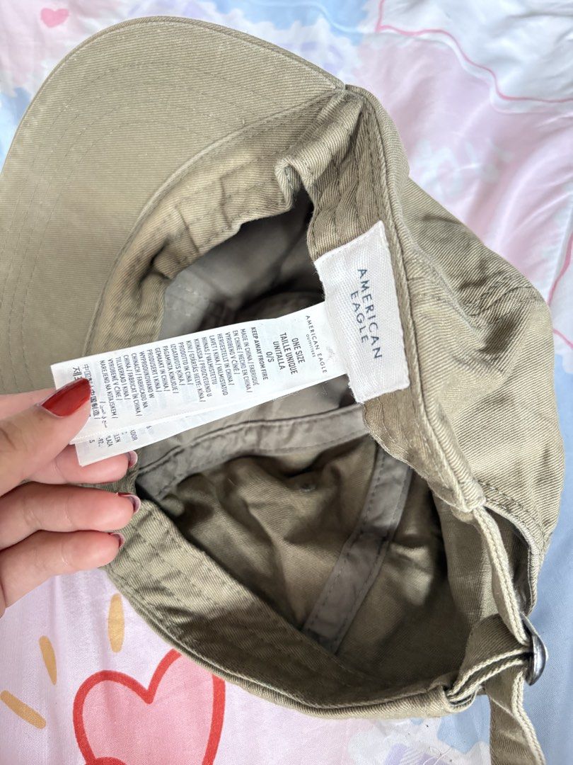 American Eagle Olive Green Baseball Cap (Category: Caps & Hats) located in Makati City. Submitted by jrnhnnh3047116 (Listing ID 1465981113, Image 1). Description: - Brand: American Eagle Outfitters - Color: Olive Green - Material: 100% Cotton with standard ventilation eyelets - Design: Embroidered eagle logo on the front - Fit: Adjustable back strap, One Size Fits Most - Condition: Interior tag intact, well-maintained - Style: Casual, streetwear,