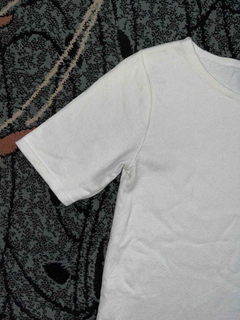 A.P.C Short Sleeve Shirt (Category: Shirts) located in Manila. Submitted by kashjulliane (Listing ID 1466118103, Image 3). Description: This item is a classic white short-sleeve crewneck T-shirt from the French minimalist label A.P.C. (Atelier de Production et de Création). The shirt features a straight, clean-cut silhouette with mid-length sleeves, a bound crew neckline, and a contrasting black branding woven tag stitched cleanly into the inner 